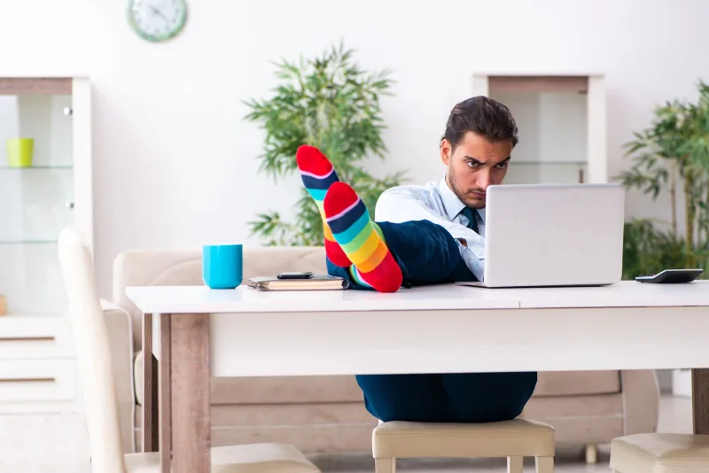 Un professionnel travaillant sur ordinateur, chaussettes colorées et pieds posés sur un bureau